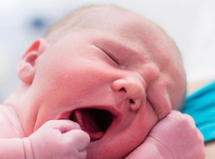 Pasgeboren baby Aila gonzend en geeuwend, close-up van roze huid en kleine vuistjes in heldere verplegingsomgeving
