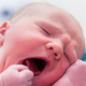 Pasgeboren baby Aila gonzend en geeuwend, close-up van roze huid en kleine vuistjes in heldere verplegingsomgeving