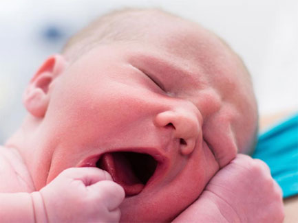 Pasgeboren baby Aila gonzend en geeuwend, close-up van roze huid en kleine vuistjes in heldere verplegingsomgeving