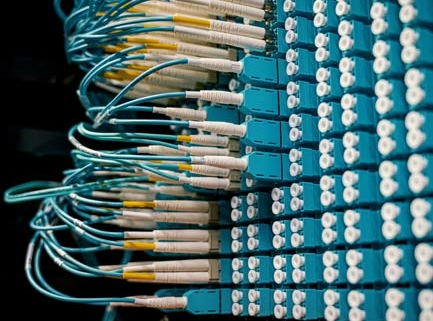 Netwerkpatchpaneel met blauwige glasvezelpatchkabels en LC-connectoren netjes aangesloten in datacenter rack, close-up beeld