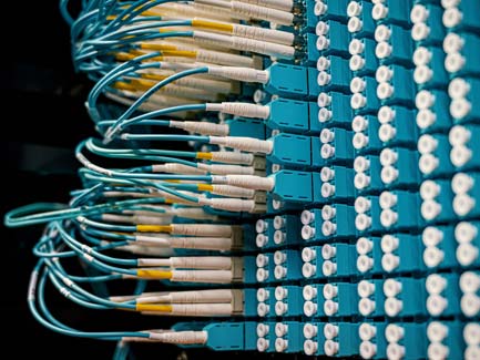 Netwerkpatchpaneel met blauwige glasvezelpatchkabels en LC-connectoren netjes aangesloten in datacenter rack, close-up beeld