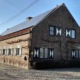 Hoeve Lakerhof traditionele bakstenen Vlaamse hoeve met witte luiken en gegolfd dak aan een kasseiweg
