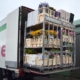 Open vrachtwagen met metalen stelling en meerdere houten kisten vol bloemen, inclusief zonnebloemen, klaar om te lossen