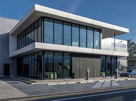 Modern two-story commercial building with large glass facades and clean white cantilevered roof under blue sky