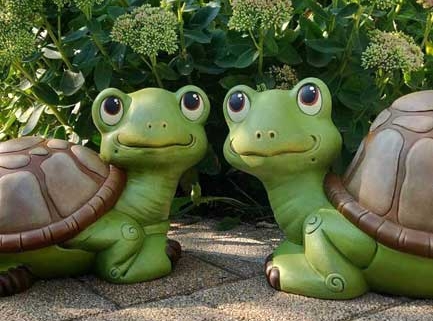 Twee vrolijke groene schildpadbeelden in een tuin voor struiken, decoratieve keramische tuindecoratie penseeltje
