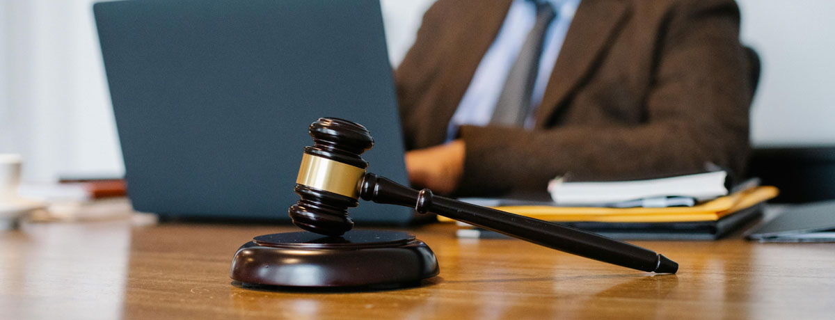 Houten rechterhamer op tafel voor laptop en dossiers, symbool voor websitewetgeving en juridisch advies online