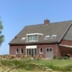 Ruime karaktervolle bakstenen woning met groot terras en tuinstoelen onder een blauwe hemel in Wouw, Nederland