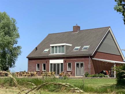 Ruime karaktervolle bakstenen woning met groot terras en tuinstoelen onder een blauwe hemel in Wouw, Nederland